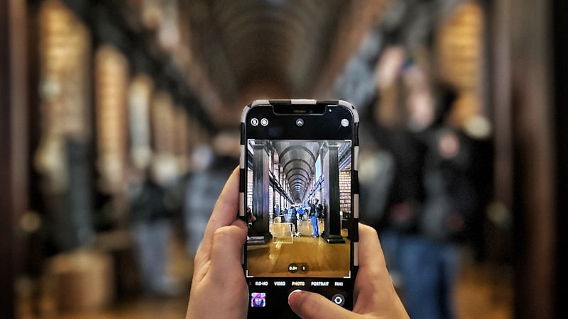 A hand holding an iPhone pointed at a document with text visually floating from the page into the phone screen