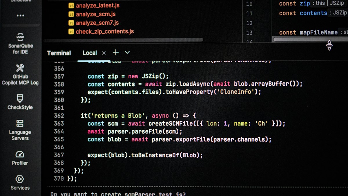 A dark code editor on a monitor with lines of JavaScript and a terminal panel